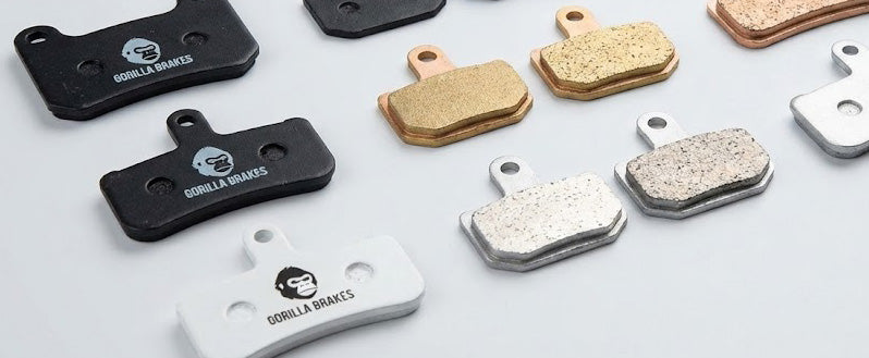 A collection of Gorilla Brakes disc brake pads displaying different compounds including sintered, organic, and ceramic with distinct backing plate colors and branding