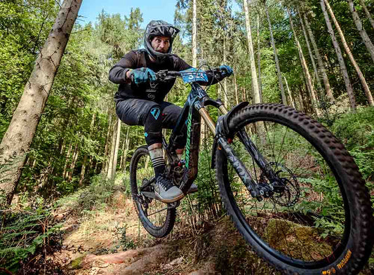 Mountain biker navigating a forest trail using SRAM CODE brakes equipped with Gorilla Brakes SRAM CODE Disc Brake Pads for maximum stopping power and control.