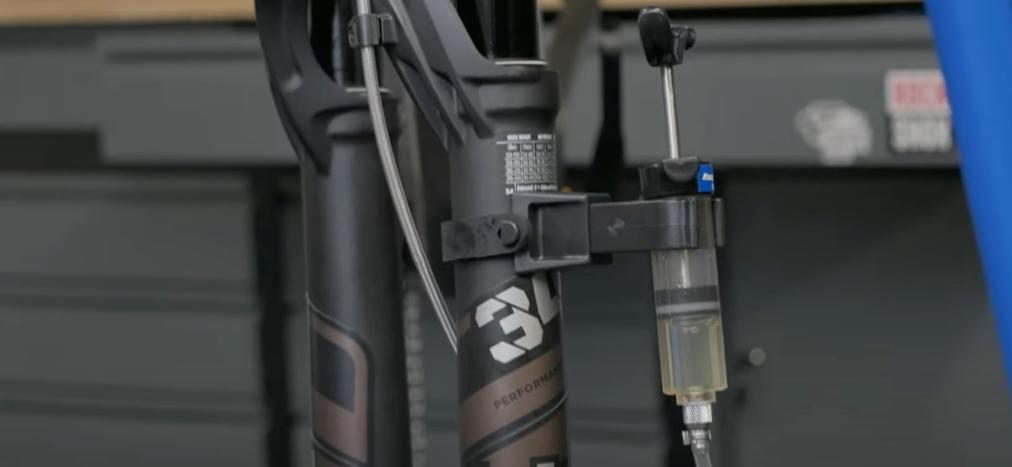 Close-up of a Shimano disc brake bleed syringe mounted to a mountain bike fork during hydraulic brake maintenance