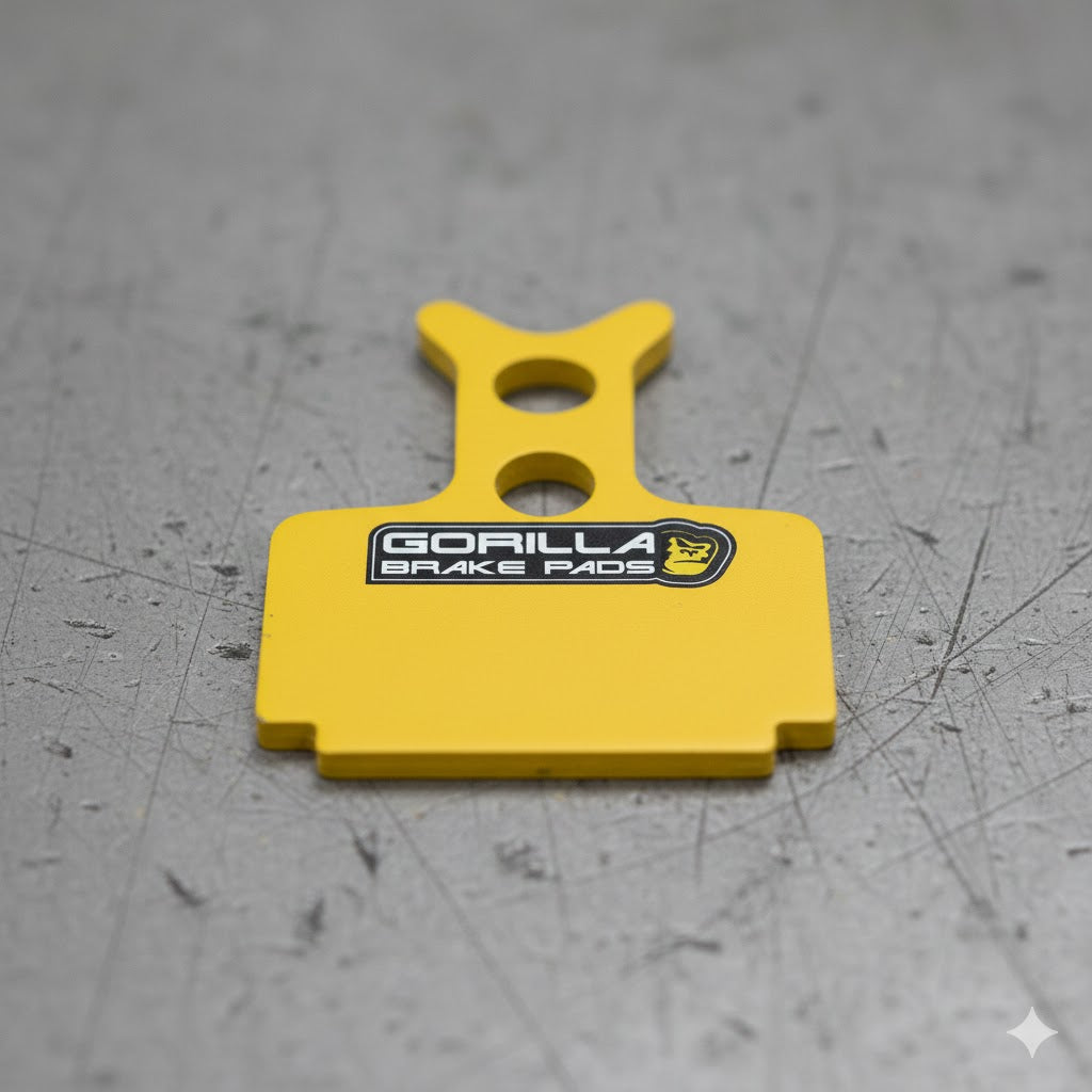 Gorilla Brakes sintered brake pads for Formula Cura road disc brakes, featuring a yellow backing plate and realistic metal texture.